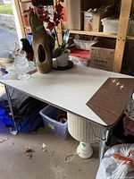 Full view of a rectangular melamine top kitchen table with woodgrain corner and white surface, metal legs, some scratches visible.