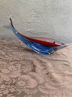 Photo showing side profile of Murano glass fish sculpture emphasizing blue and red coloration and overall shape.