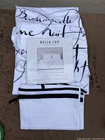 Folded white duvet cover with black French and English script writing, showing packaging label with product details and brand name Bella Lux