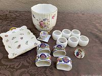Lot contents with Coalport jardiniere, small teacup and saucer, six white napkin rings, four floral April Cornell napkin rings (one cracked) and Skye McGhie plate