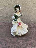Front view showing the lady in Victorian dress holding red roses bouquet.