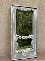 Full front view of the two-part shabby chic mirror with ornamental carved frame and distressed gray paint.