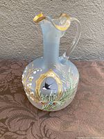 Front side view of frosted glass jug showing detailed hand painted bird and flora design with gold accents