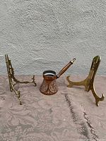 All three items displayed: vintage Turkish coffee pot with wooden handle and two brass picture stands on a floral cloth