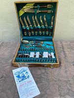 Full open case displaying the complete bronze cutlery set securely arranged and including advertising leaflet from Johnnys Gems.