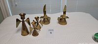 Five brass decor items on white surface: three angels as candle holders and two birds as figurines; all polished brass.