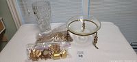 Photo of all items including glass bowl with brass legs, crystal vase, and gold candle decor pieces grouped together on a white surface.