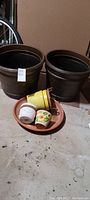 Two large dark brown planters and a tray holding smaller pots including two yellow metal pots and two ceramic pots, one with floral design.