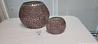 Full view of two round mauve and dark mauve cut glass vases with mosaic glass pattern on white surface