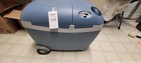 Front view of blue Mobicool electric cooler with wheels visible at base.