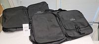 Two black Samsonite duffle bags displayed side by side on a flat surface, front and top visible showing zipper compartments and buckle flap.