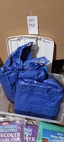 Photo of 2 blue tarps in a clear bin with shrub covers and packaging for shrub covers around them.