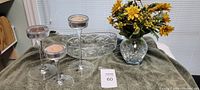 Full set showing clear glass vase with yellow artificial flowers, three glass candle holders of different heights with candles, and oval cut-glass crystal bowl in background.