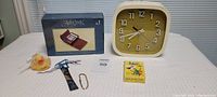 Wide shot showing all items: Caravelle clock, poker set in box, Hearts card game, yellow rubber ducky, metal gun shaped item, gold chain bracelet