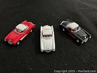 Top-down view of the 3 Corvette die cast cars showing their colors and details on a black background.