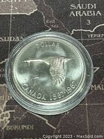 Obverse side of the 1967 Canadian silver dollar coin showing a flying Canada goose with 'DOLLAR' and 'CANADA 1867-1967' inscriptions, coin encased in clear protective plastic.