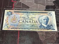 Front side of 1972 Canadian 5 dollar banknote showing Sir Wilfrid Laurier portrait, serial numbers, and Canadian coat of arms.