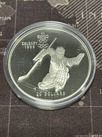 Obverse side of the coin showing hockey player artwork, Calgary 1988 logo, and 20 dollar denomination.