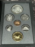 View of the seven proof coins displayed in black foam holder, showing both sides of coins in high quality with visible detail