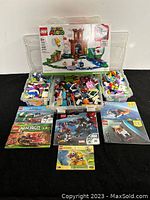 Assorted LEGO sets and manuals displayed with loose pieces in plastic storage box