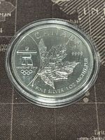 Obverse side showing a detailed maple leaf, Vancouver 2010 Olympics logo, and silver purity markings.