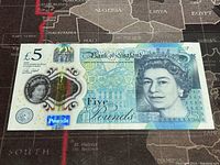 Front side of 2016 UK £5 polymer banknote showing Queen Elizabeth II portrait and holographic security features.