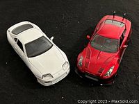 Two die cast sports cars, one white and one red, shown from the front and top angles.