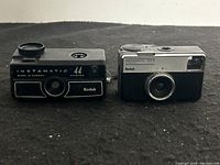 Front view of Kodak Instamatic 44 and Instamatic 133-X side by side against a plain background.