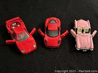 Top-down view of three die cast sports cars on a black surface, showing open doors and details