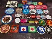 Photo showing entire collection of assorted round buttons and fabric badges arranged on a dark surface.