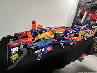 Seven various Nerf toy blasters shown on a black surface, including N-Strike Elite, Mega, and Rival series.