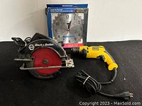 Photo showing Black & Decker circular saw, Dewalt drill, and Mastercraft wall clock in box on white surface