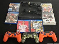 Overall view showing PS4 console, three controllers, six game cases