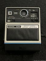 Front view of the Kodak EK4 instant camera showing lens, print control, flash indicator, and branding.