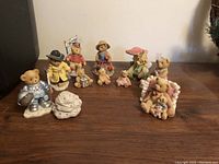 Group of 10 Cherished Teddies figurines displayed on a table, including astronaut, private eye, conductor, farmer, and St. Patrick's Day teddy.