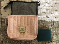 Two makeup bags and a jewelry case displayed on a quilted surface