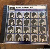 Front cover of The Beatles CD titled 'A Hard Day's Night' showing a blue background with multiple black and white portraits of the band members arranged in a grid.