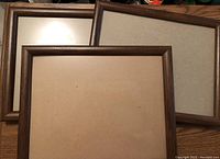 Three 11x14 picture frames with dark wood finishes laid overlapping showing cream mats inside for 8 x 10 photos.