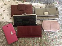 Photo of five wallets and a bright pink phone case on floral fabric