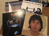 Four vinyl album covers including Wings Across America, London Town, Back to the Egg, and McCartney II laid out together.