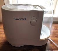 Side view of Honeywell portable humidifier showing brand, control dial, and water tank.