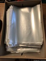 Box containing a large stack of clear plastic sheet protectors with 3-hole punched edge.