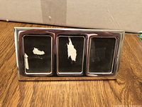 Silver plated frame with three photo openings on wooden surface