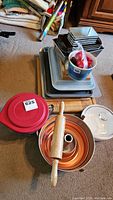 Full view of the baking items included in the lot, showing baking sheets, pans, cutting boards, rolling pin, and batter bowl with lid.