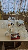 Full lot of vintage glassware and dishware including jars, mugs, cups, plates, and juicer on table
