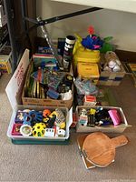 Overview of assorted children's toys in boxes and containers including Lego materials, books, and small toys