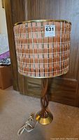 Full view of lamp showing wooden sculptural base, metal accents, and cylindrical shade with wood slats and metal grid.