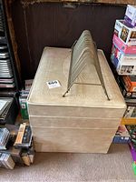 Side view of beige storage ottoman with embossed detailing and record holder on top