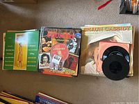 Photo of assortment of vinyl record album covers on carpet including compilation of country music and various artists.