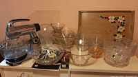 Wide shot showing the Sunbeam Mixmaster with glass mixing bowl and assorted crystal and glass bowls, alongside a wooden tray with painted flowers